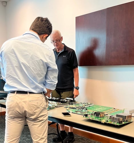 Jake Hertz (blue) inspecting Tektronix PCBs with Tim Bieber (black).