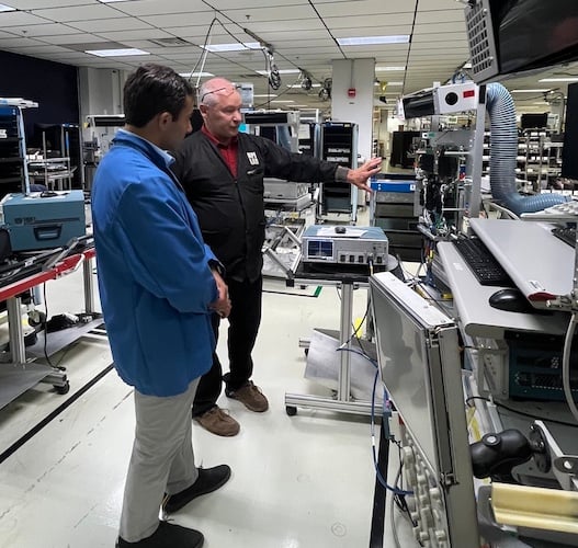 All About Circuit contributor Jake Hertz (left) and Tektronix’s Jeff Schuh (right) inspect a test station on the Tektronix manufacturing floor.