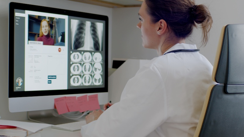 Telemedicine - a doctor consults with a patient remotely with medical imaging visible on screen